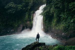 travel photography waterfall man standing on rock